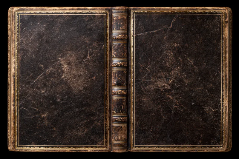 Open antique leather-bound book laid flat showing both covers against black background