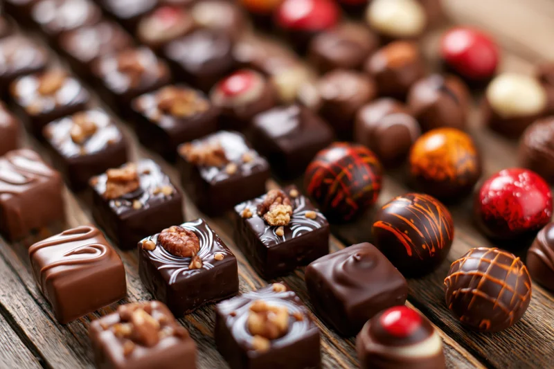 Assorted artisan chocolates arranged densely on a wooden surface