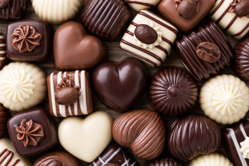 Assorted luxury chocolate pralines and truffles arranged on a wooden surface in a flat lay top view