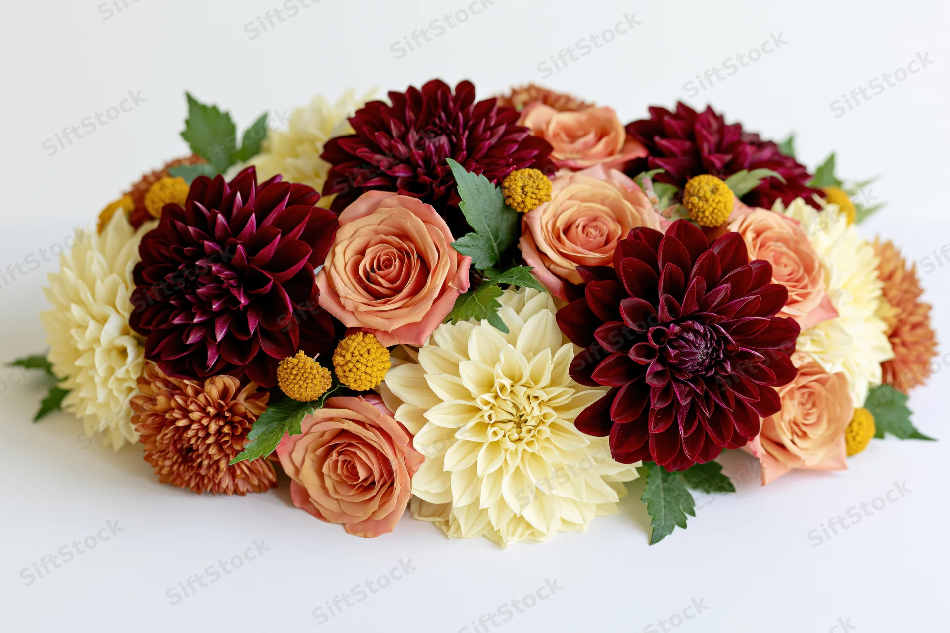 Autumn floral arrangement with dahlias, roses, and greenery on white surface