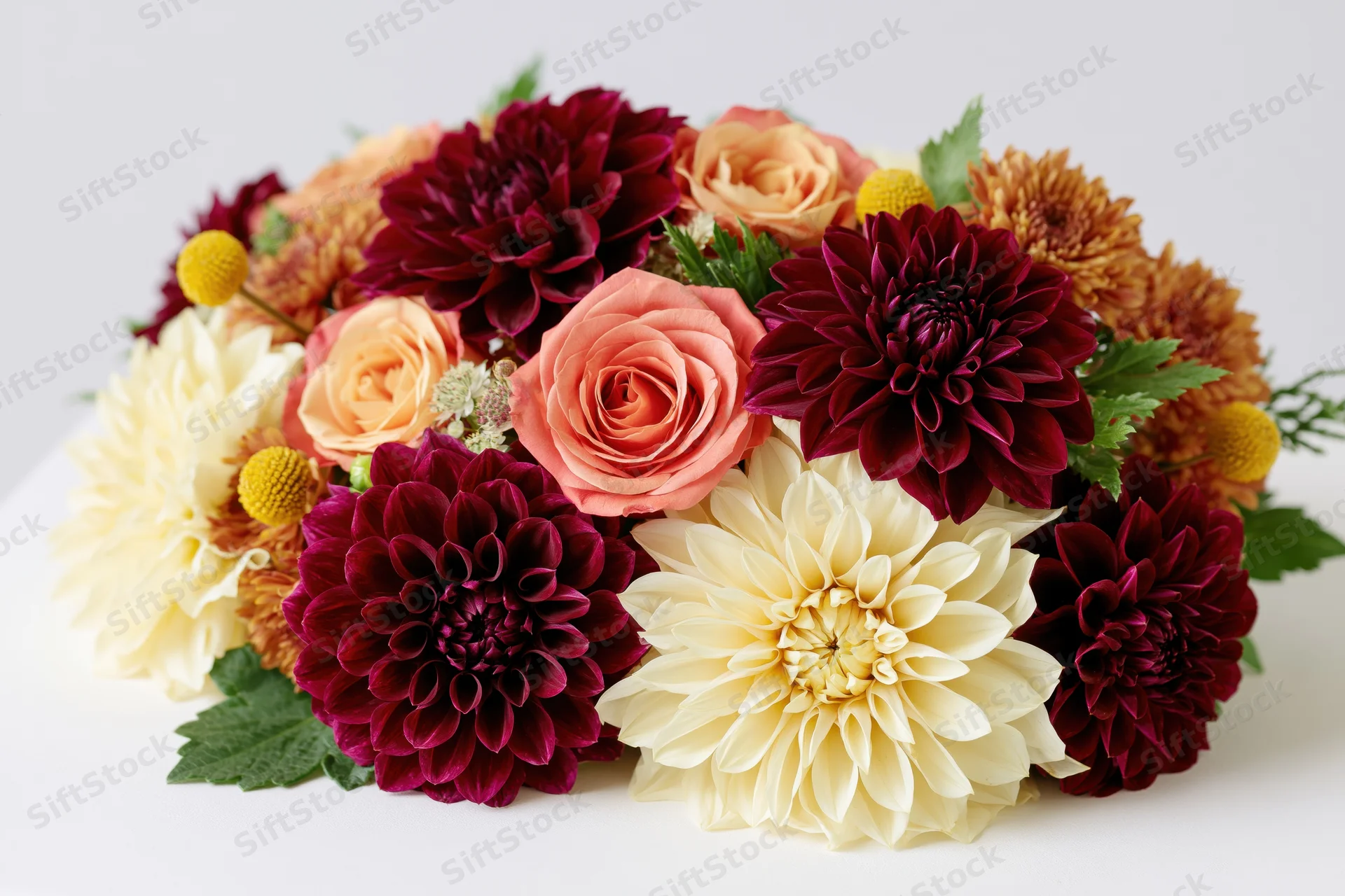 Autumn floral arrangement with dahlias, roses and chrysanthemums on white surface