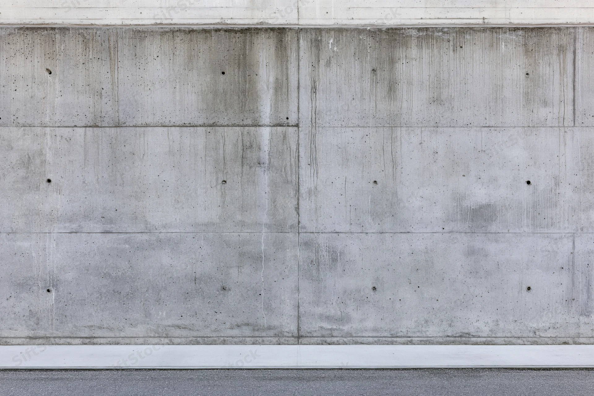 Wide flat view of a bare concrete wall with horizontal and vertical seams and weathered texture