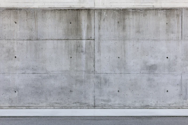 Wide flat view of a bare concrete wall with horizontal and vertical seams and weathered texture