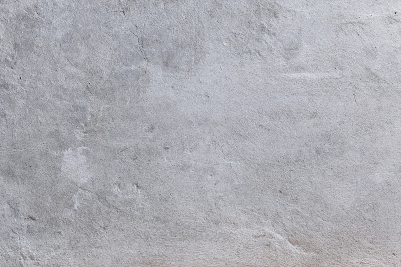 Close-up of a rough gray concrete wall surface with cracks and texture filling the frame