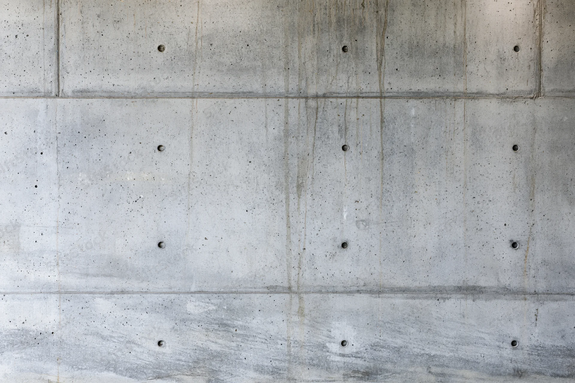 Bare poured concrete wall with visible formwork holes and seams filling the frame