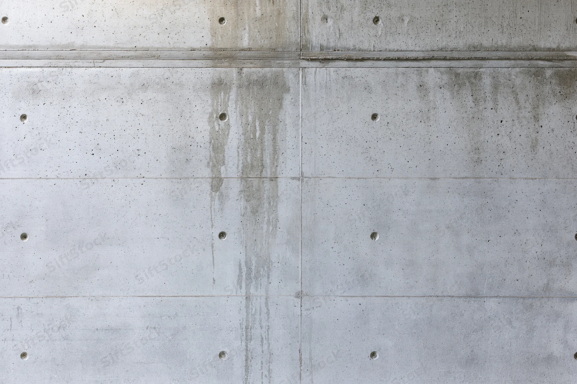 Close-up of a bare poured concrete wall with visible seams and formwork holes