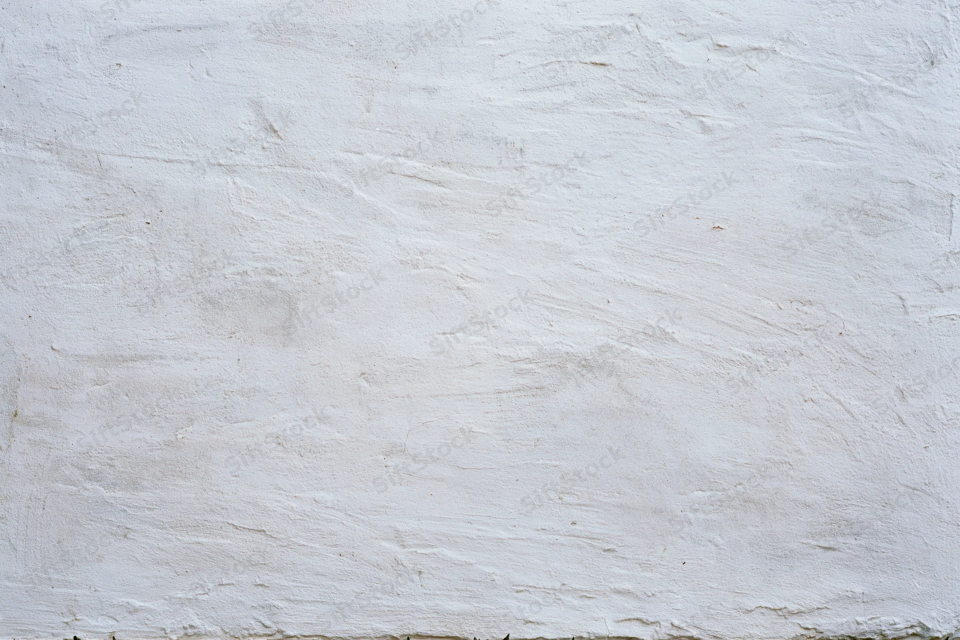 White plastered concrete wall with uneven texture and visible surface imperfections
