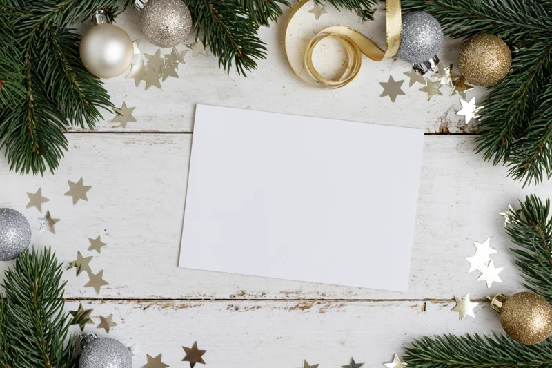 Blank white greeting card on white painted wood surrounded by christmas decorations