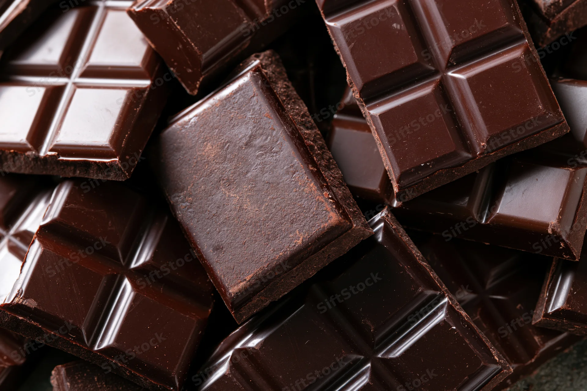 Broken dark chocolate bars stacked and scattered in closeup view