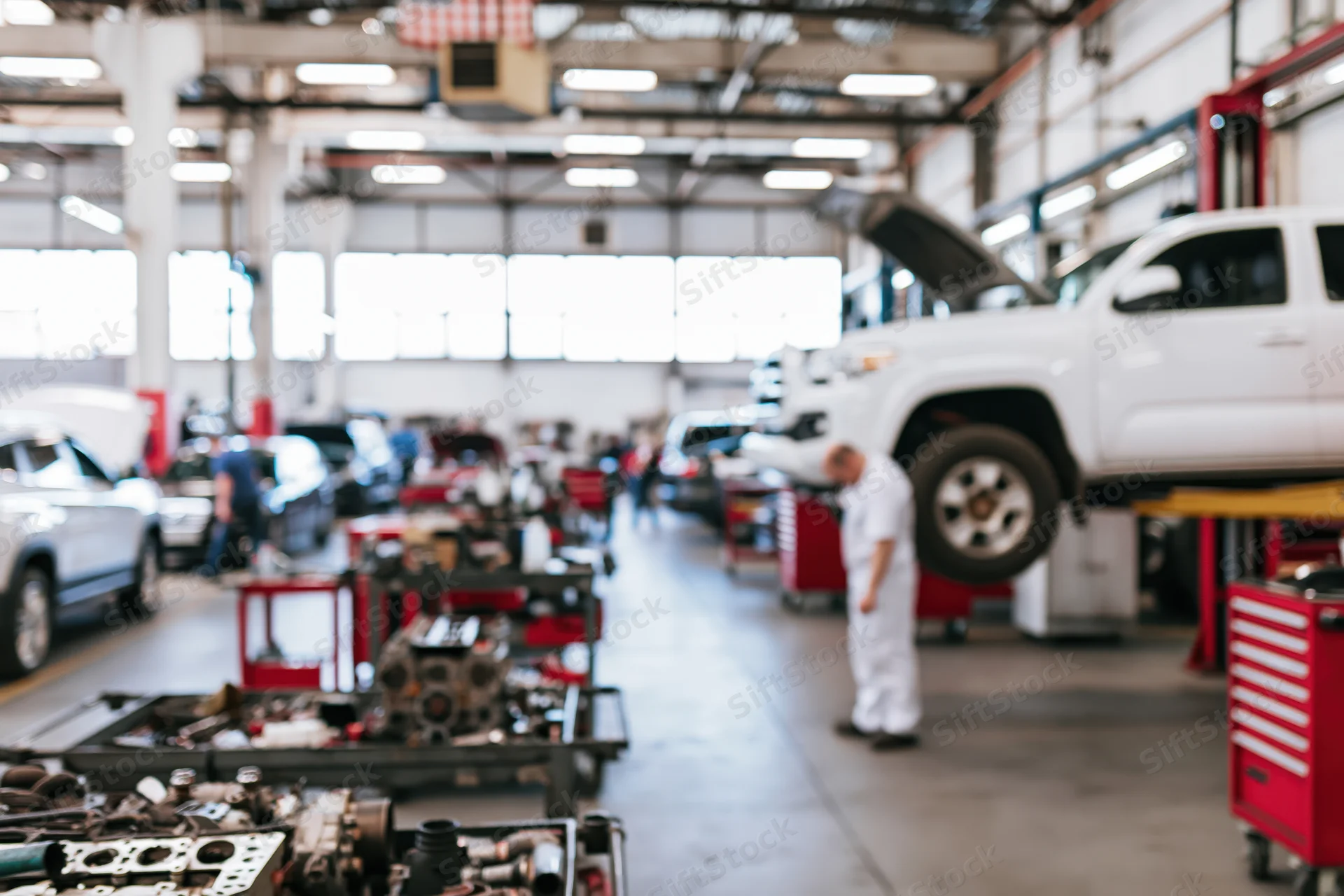 Mechanic working under white pickup truck in automotive repair shop interior