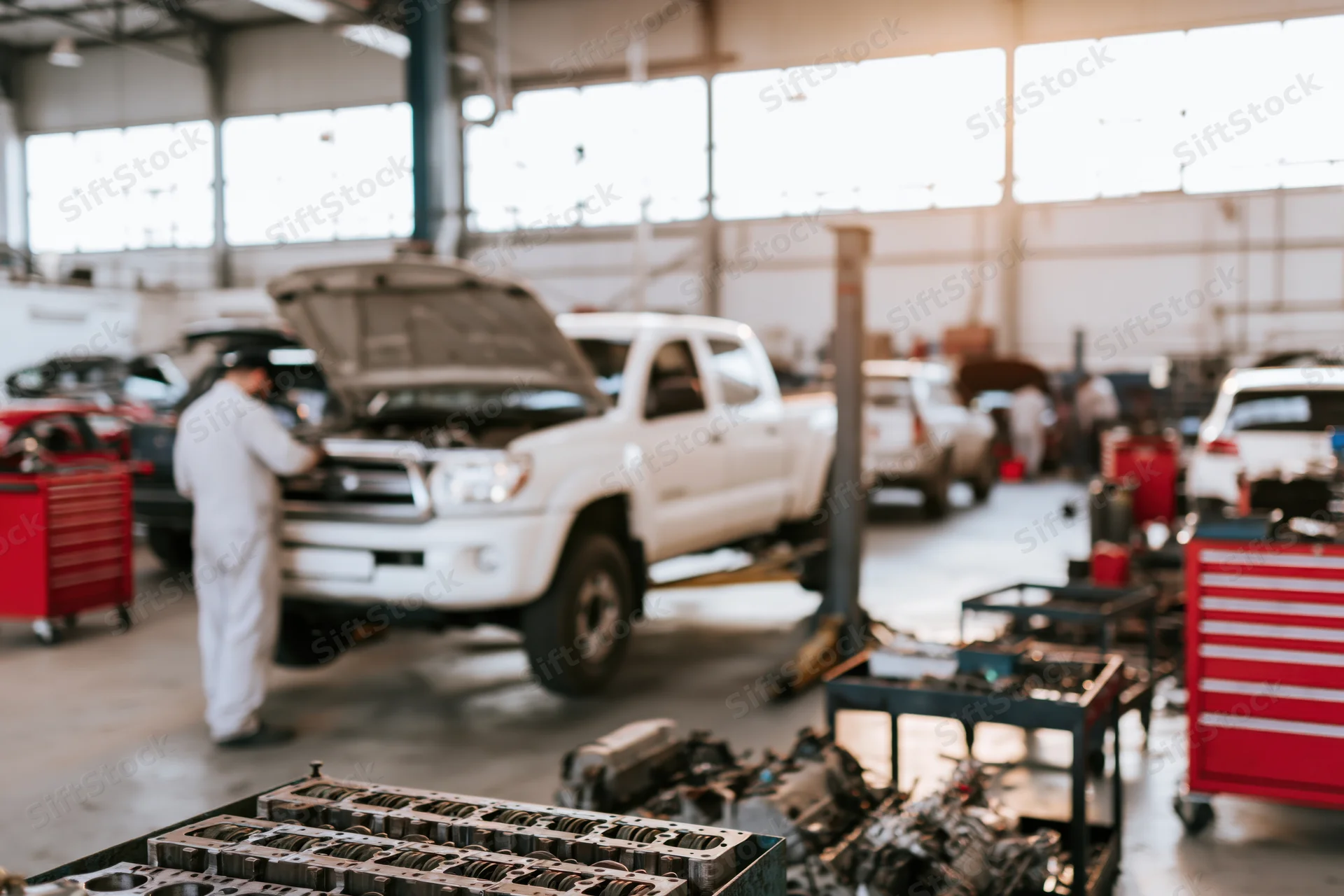 Mechanic working on white pickup truck in automotive repair shop interior