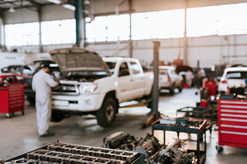 Mechanic working on white pickup truck in automotive repair shop interior
