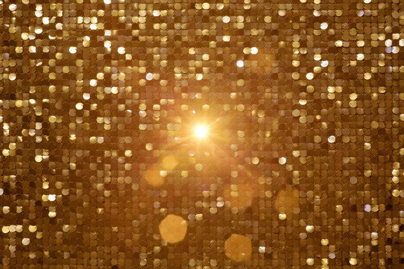 Close-up of gold sequin fabric with sparkling light reflections filling the frame