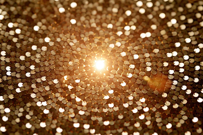 Close-up of gold sequins sparkling with light in a flat frame