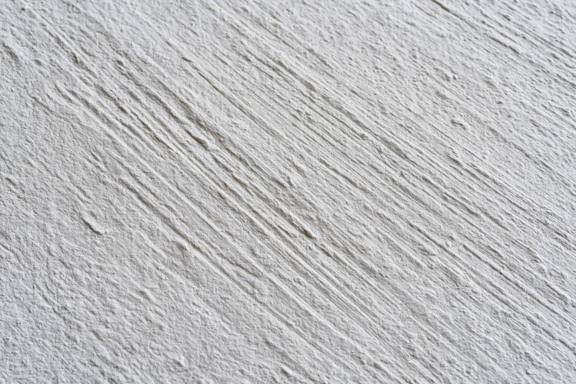 Close-up of rough stucco wall surface with diagonal texture pattern