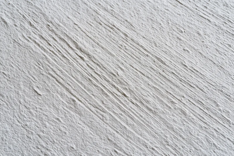 Close-up of rough stucco wall surface with diagonal texture pattern