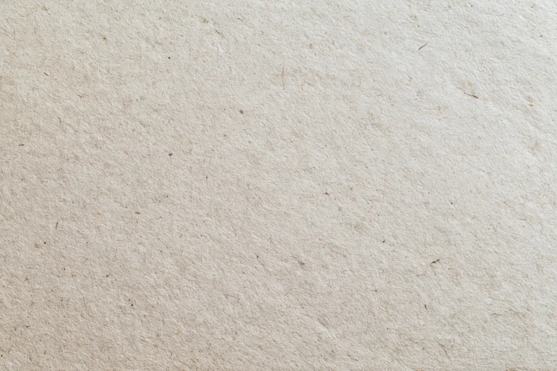 Close-up flat lay of a sheet of recycled kraft paper filling the frame with natural fiber texture