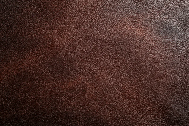 Close-up of aged dark brown leather surface with visible grain and texture