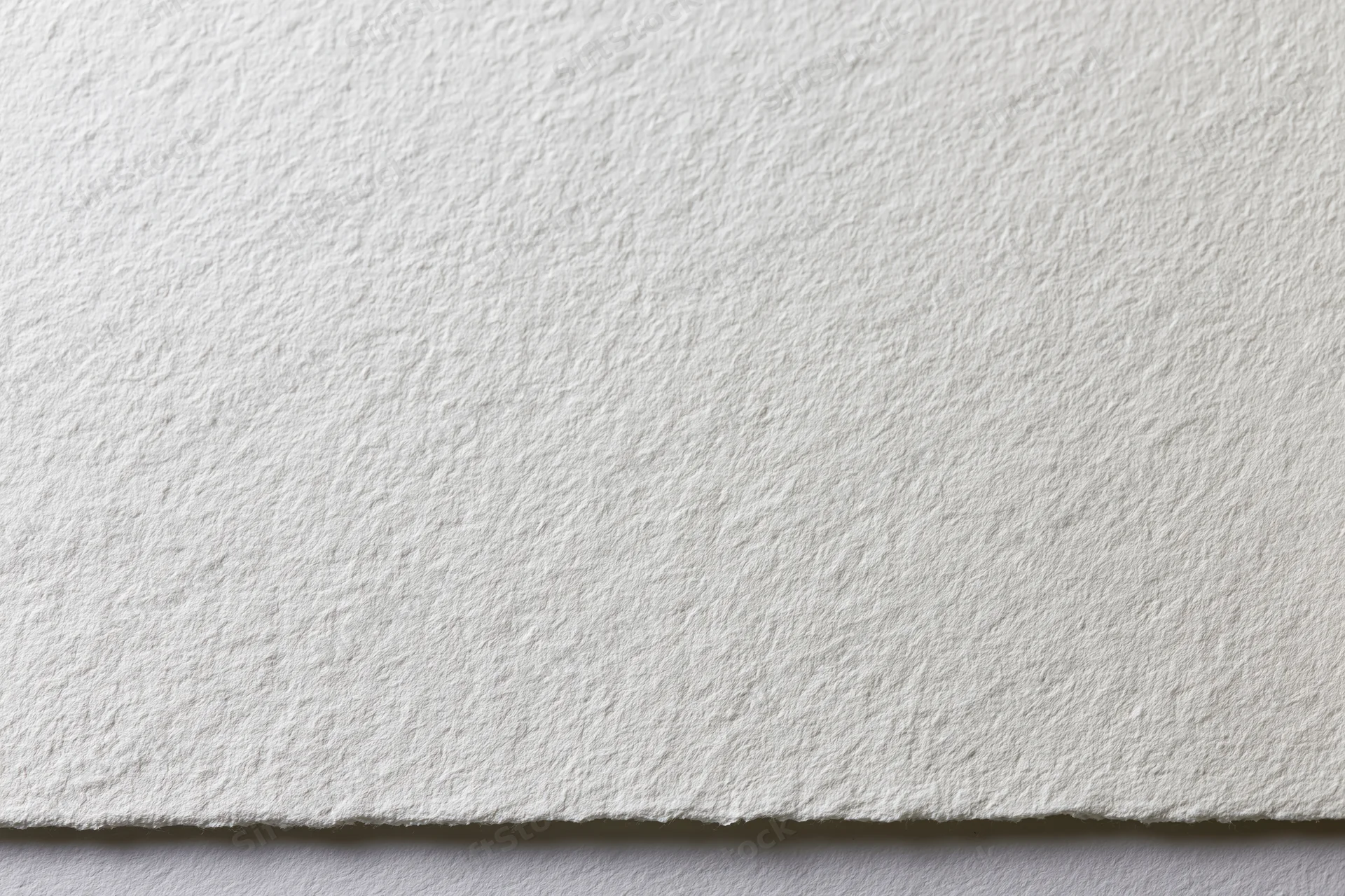 Close-up of white watercolor paper texture with torn edge showing fibrous surface