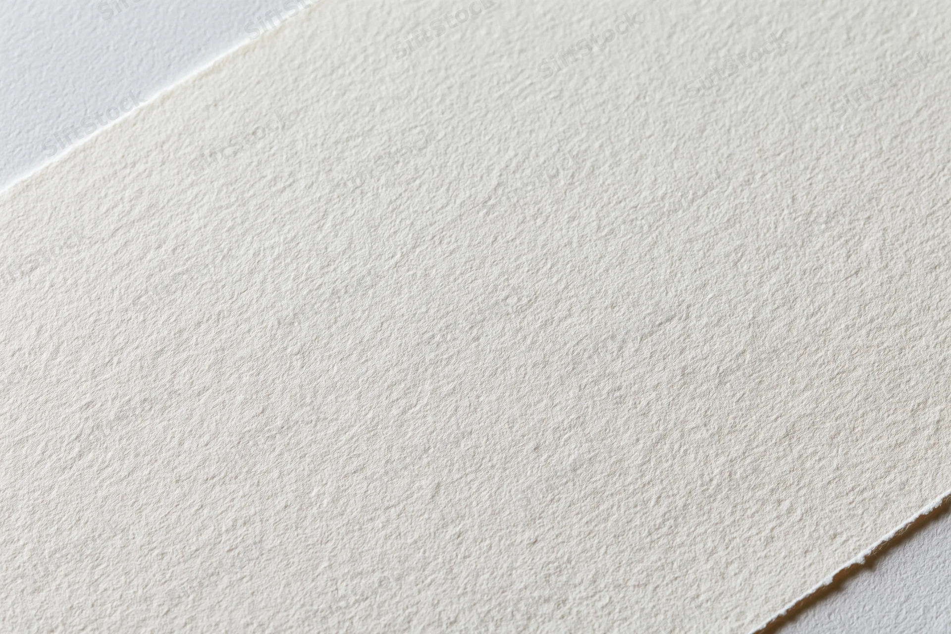 Close-up of plain white watercolor paper texture on a flat surface