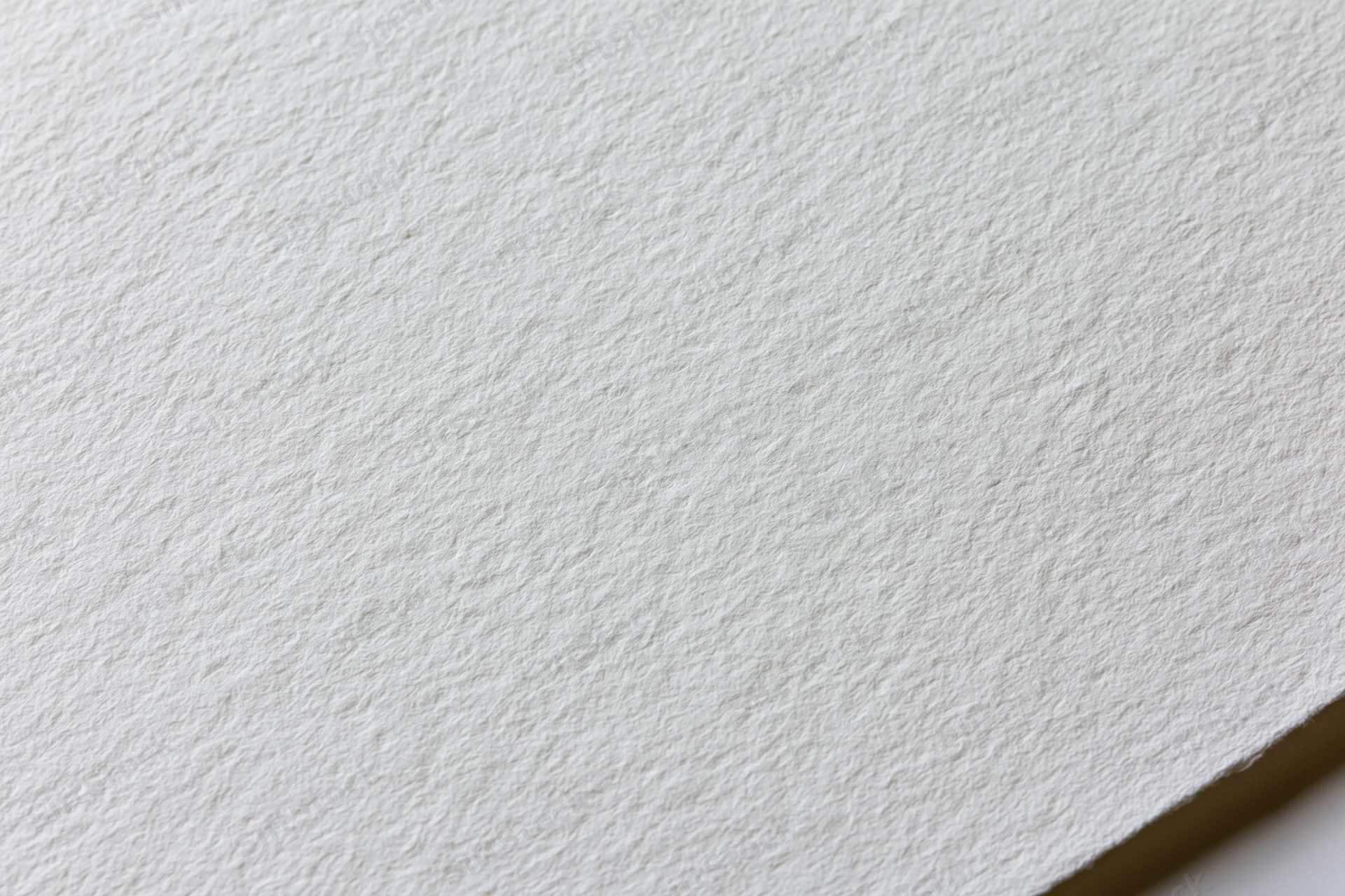 Close-up of plain white watercolor paper texture with visible grain and corner fold
