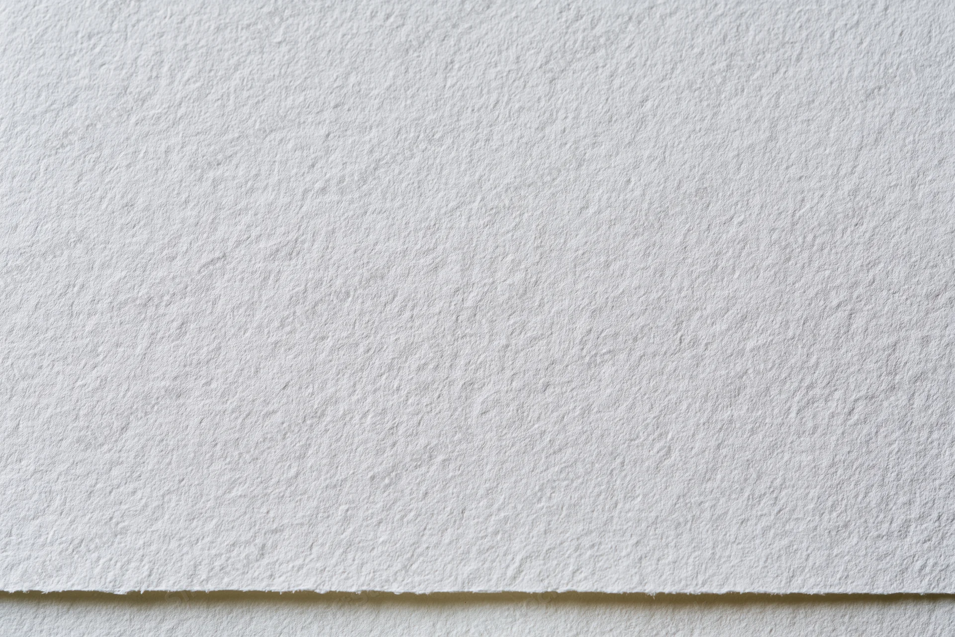 Close-up of white watercolor paper texture with visible fibers and edge detail