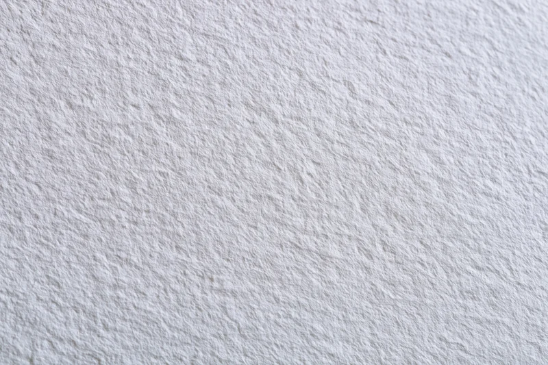 Close-up of white watercolor paper surface with textured grain filling the frame