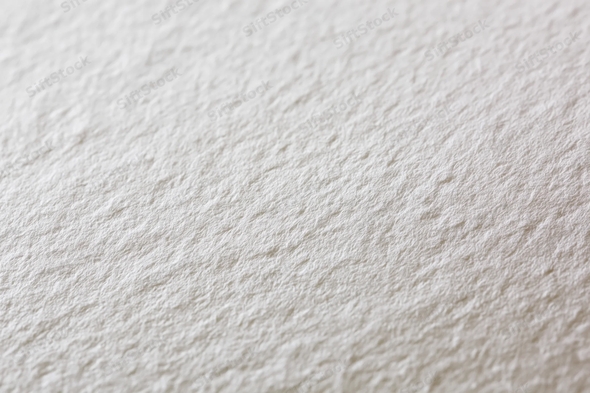 Close-up of white watercolor paper surface with textured grain filling the frame