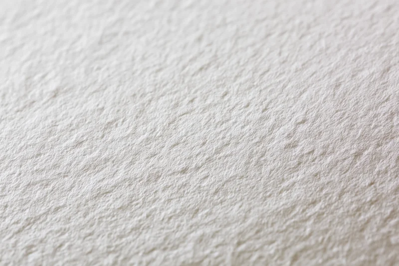 Close-up of white watercolor paper surface with textured grain filling the frame