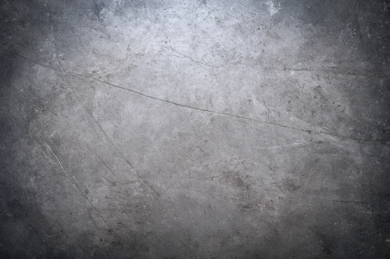 Close-up of a weathered concrete wall surface with cracks and scratches, showing texture and grunge details
