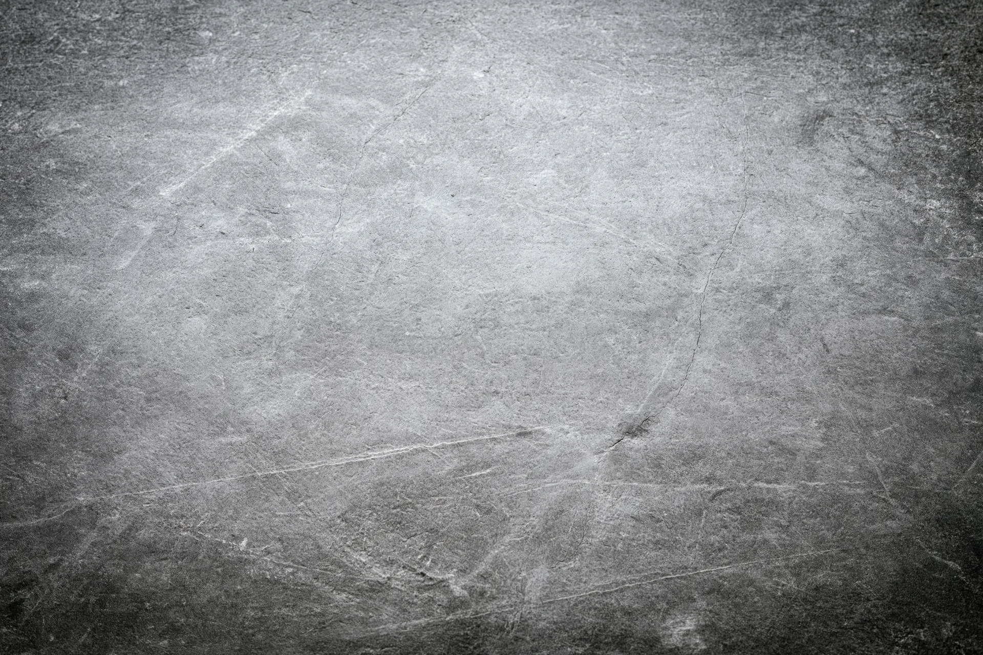 Close-up of a weathered concrete wall surface with cracks and scratches
