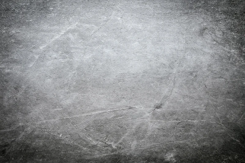 Close-up of a weathered concrete wall surface with cracks and scratches