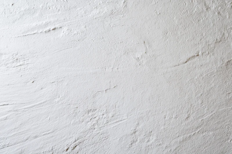 Close-up of white painted plaster wall surface with textured finish