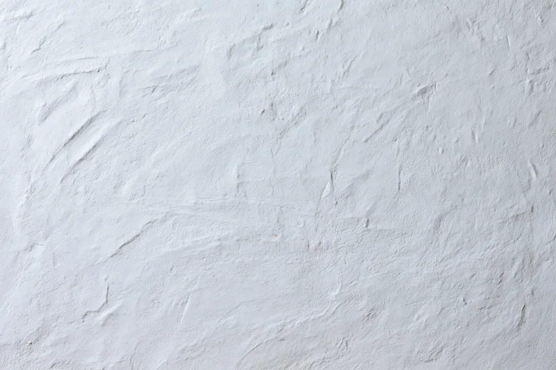 Close-up of white plastered wall surface with rough texture