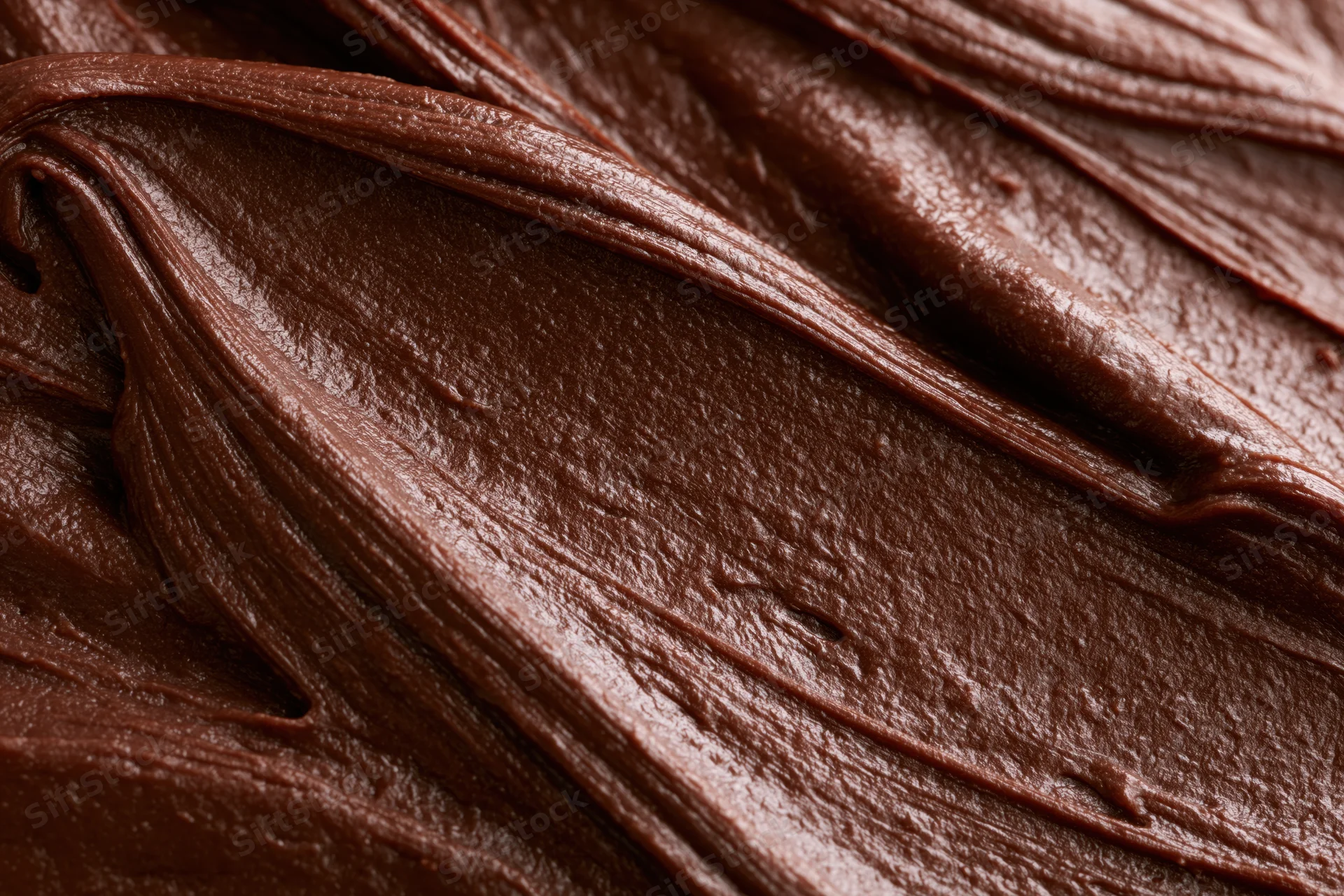 Close-up of thick chocolate frosting with swirling texture filling the frame