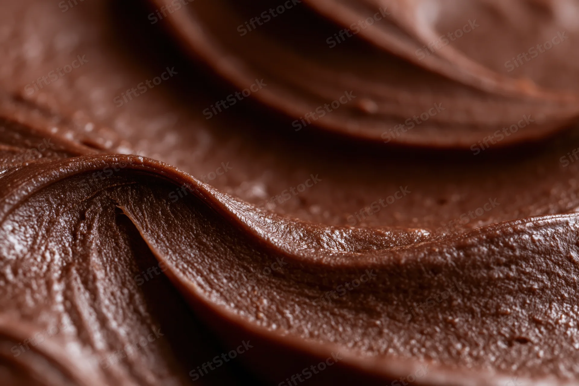 Close-up of thick chocolate frosting with smooth swirls and glossy texture