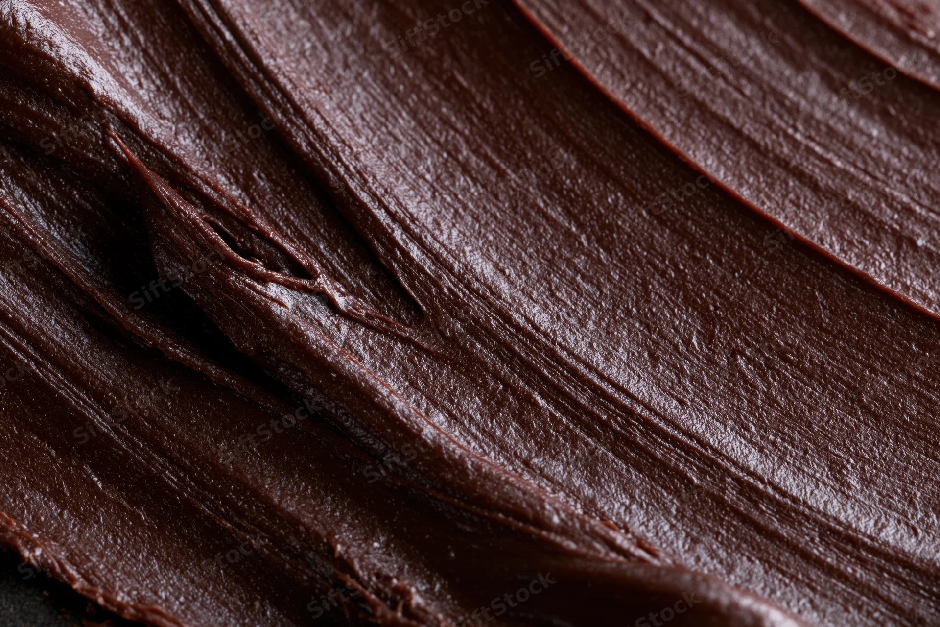 Close-up of thick chocolate spread with glossy texture and smooth folds