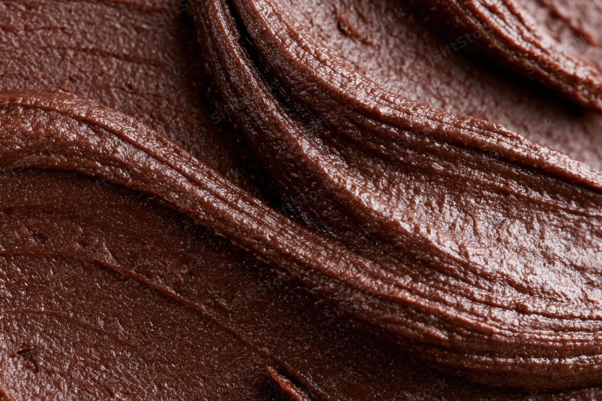 Close-up of thick chocolate frosting with swirling texture
