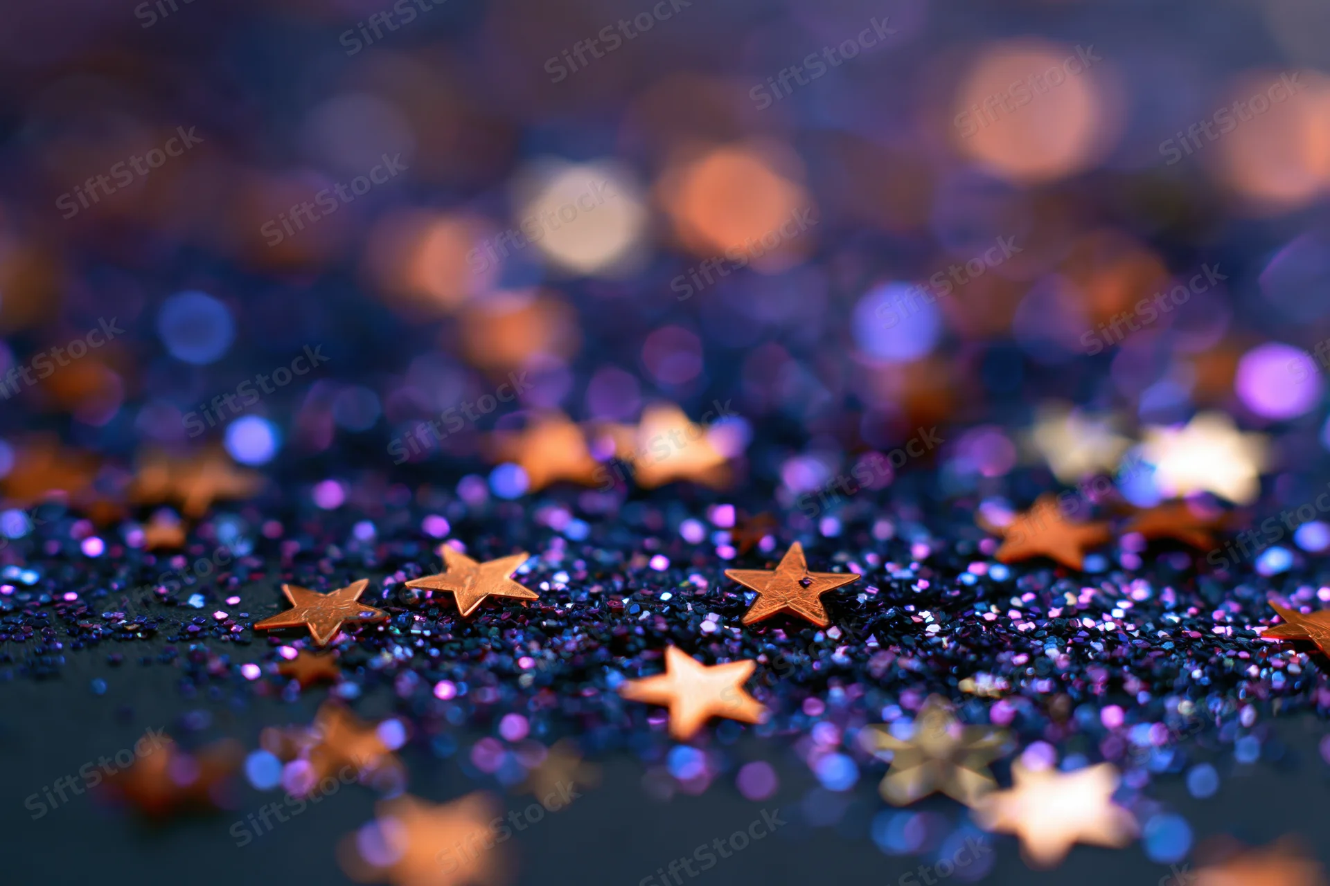 Star-shaped glitter scattered on a shimmering iridescent surface with bokeh lights in the background