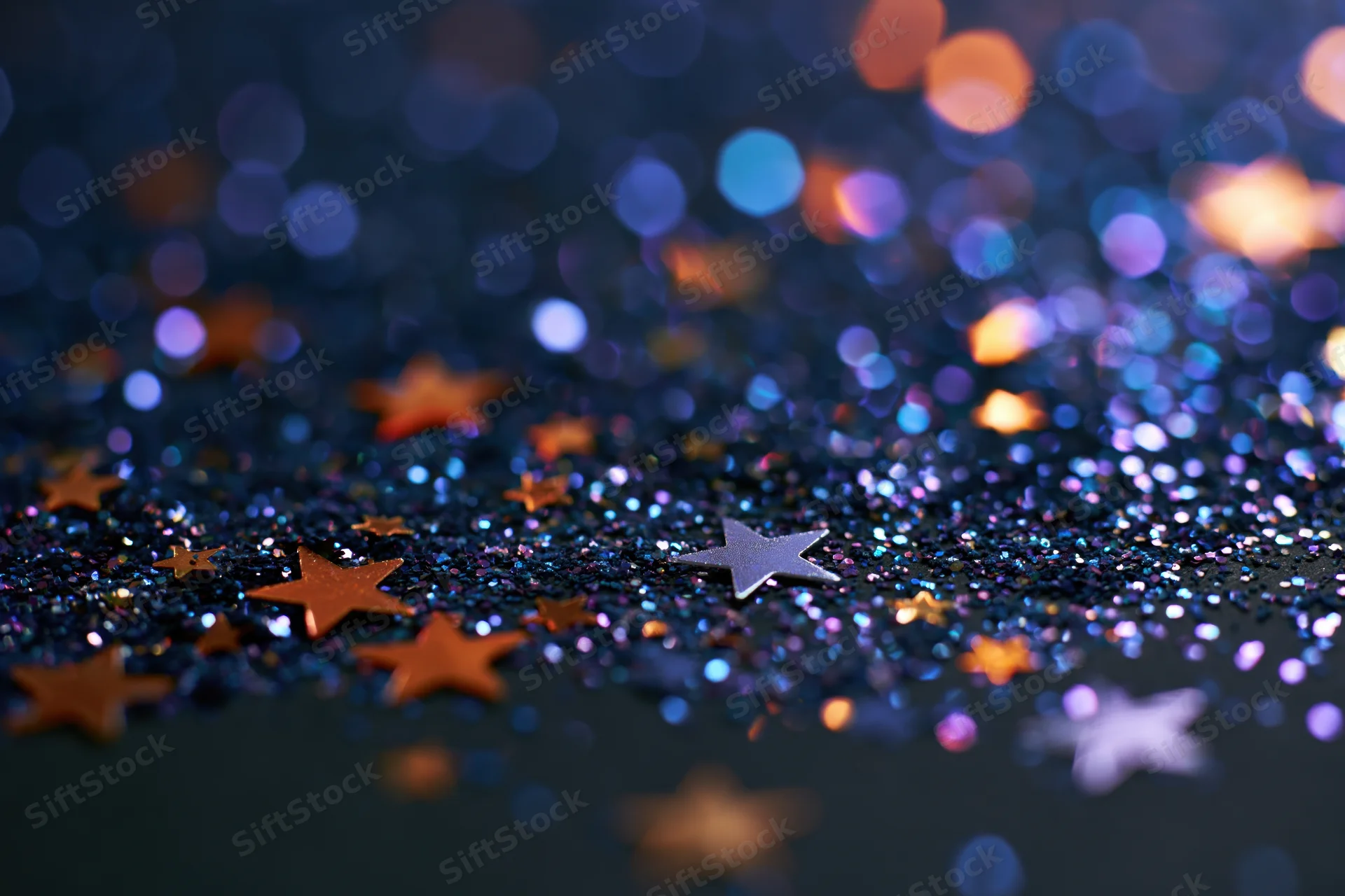 Iridescent glitter and star-shaped confetti scattered on a dark surface with bokeh lights in the background