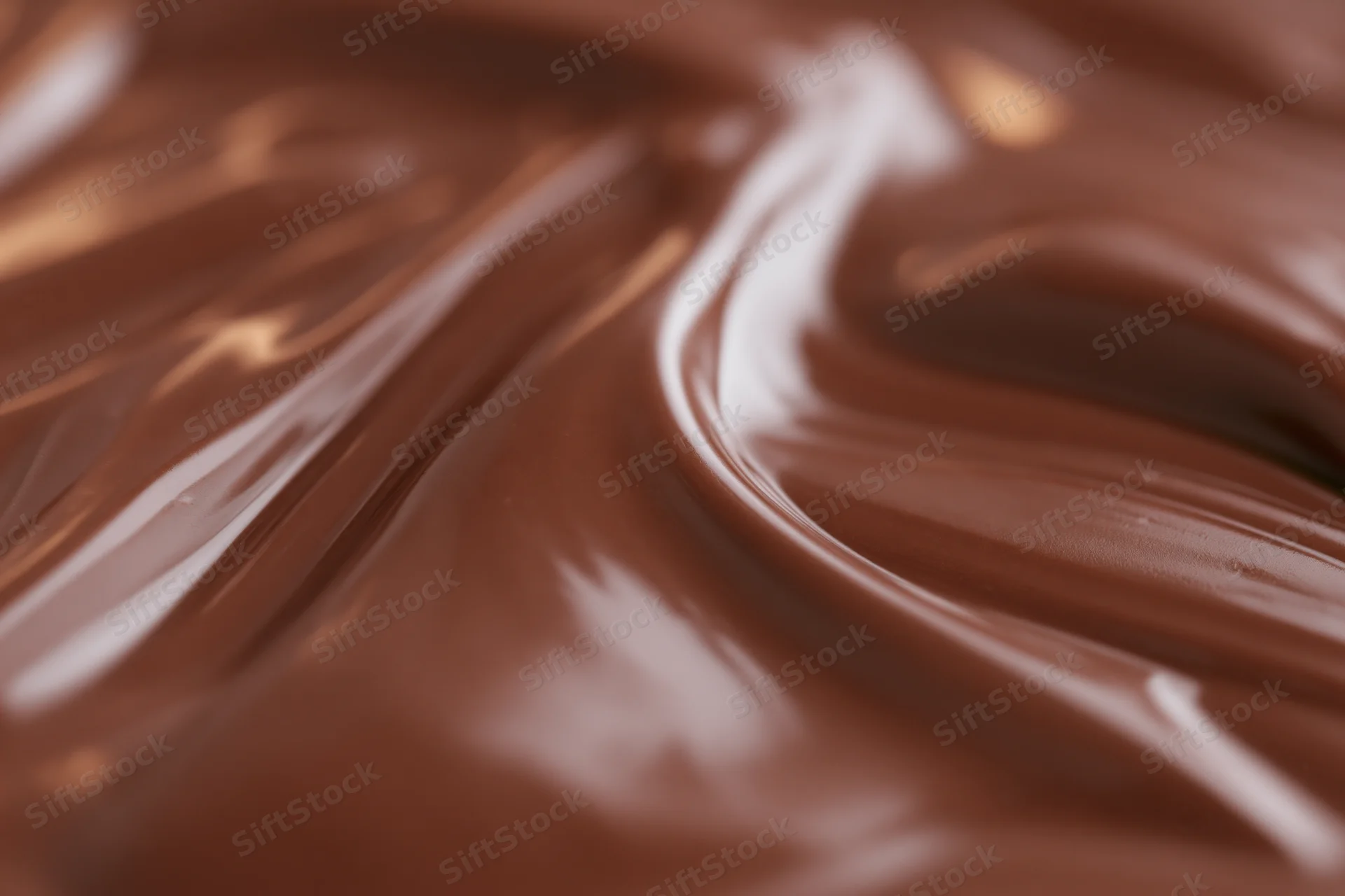 Close-up of smooth melted milk chocolate with swirling texture and glossy surface