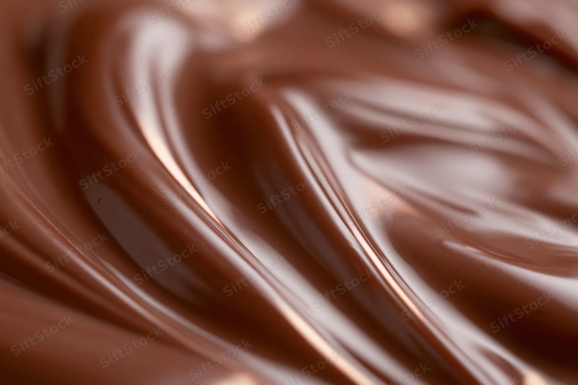 Close-up of smooth melted milk chocolate swirling in a glossy texture
