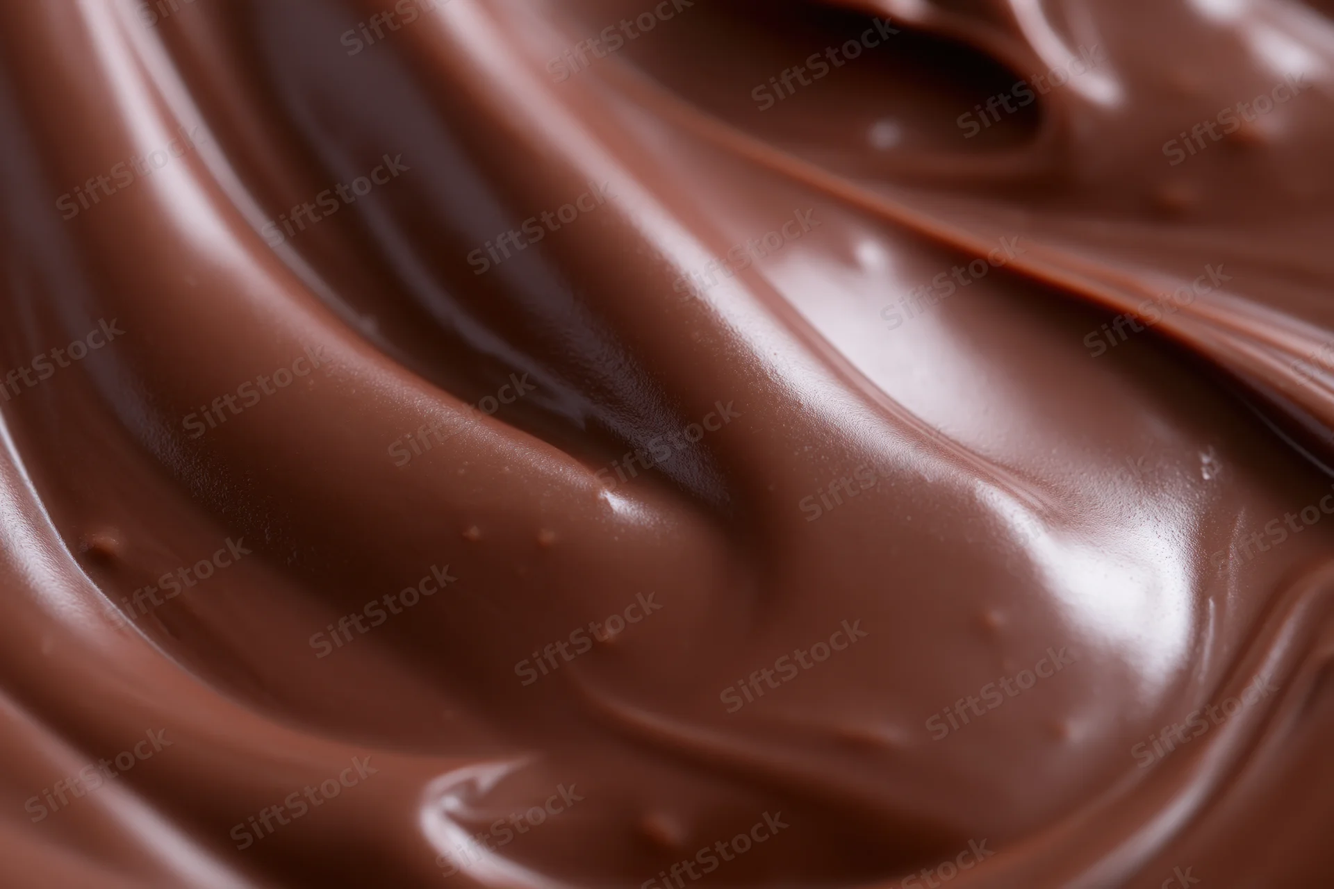 Close-up of smooth melted milk chocolate spread with swirling texture