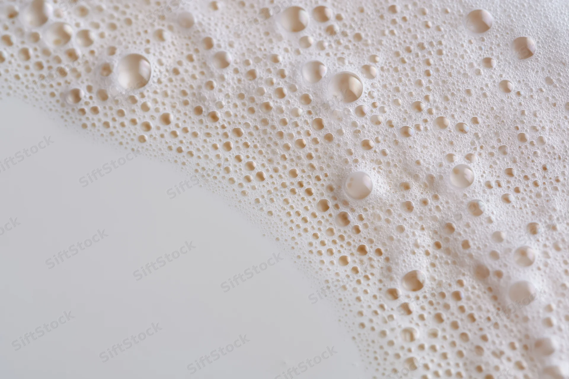 Close-up of white milk foam with bubbles on a smooth surface