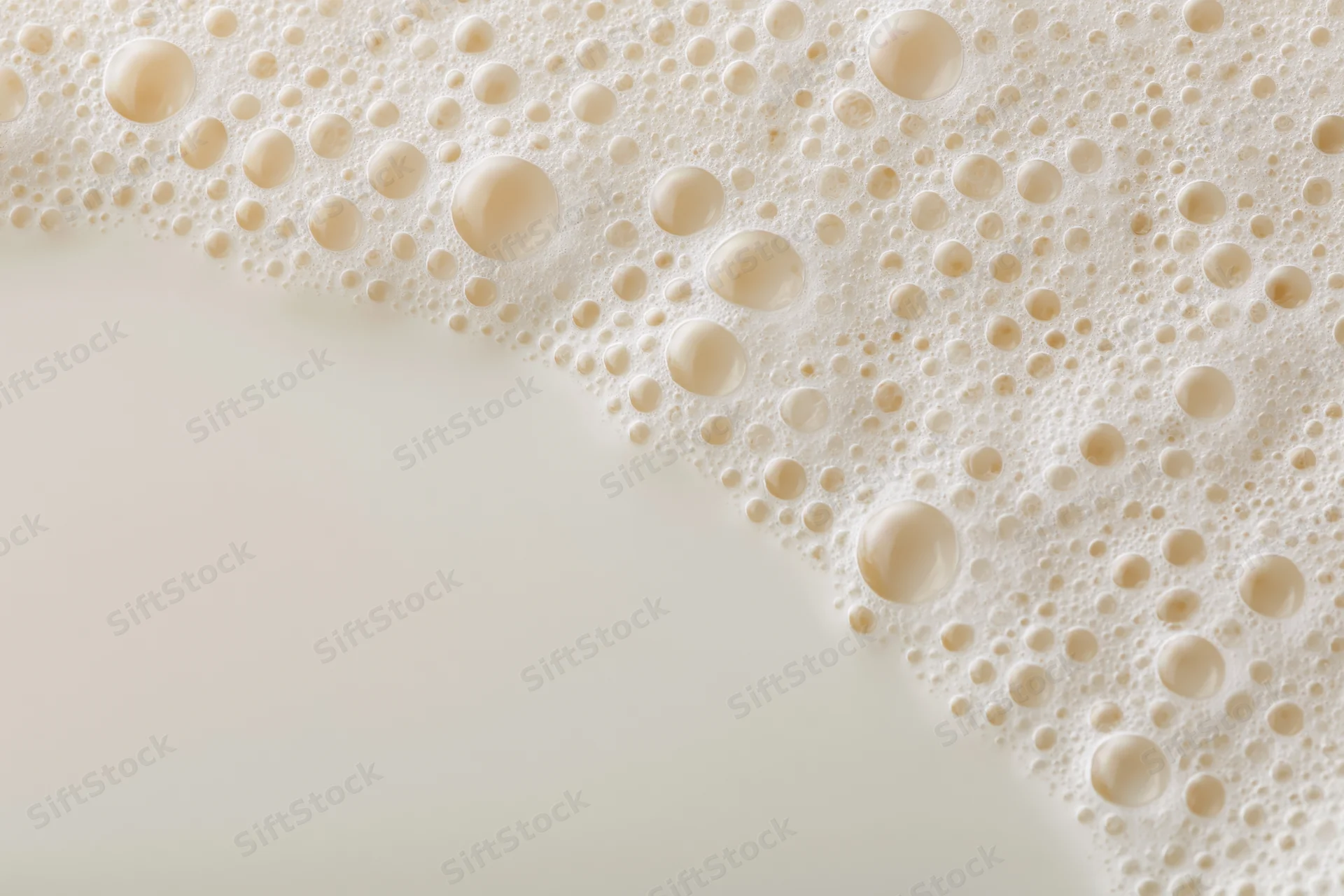 Close-up of white milk foam with bubbles on a smooth surface