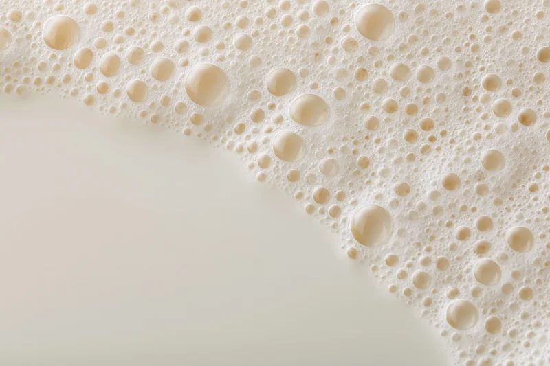 Close-up of white milk foam with bubbles on a smooth surface