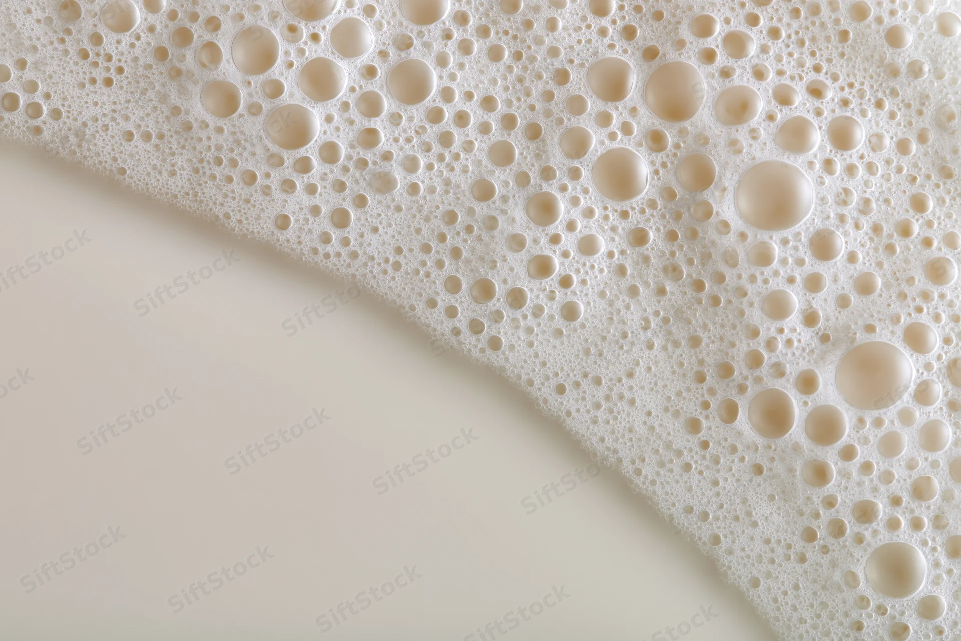 Close-up of white milk foam with bubbles on a smooth surface