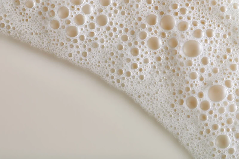 Close-up of white milk foam with bubbles on a smooth surface