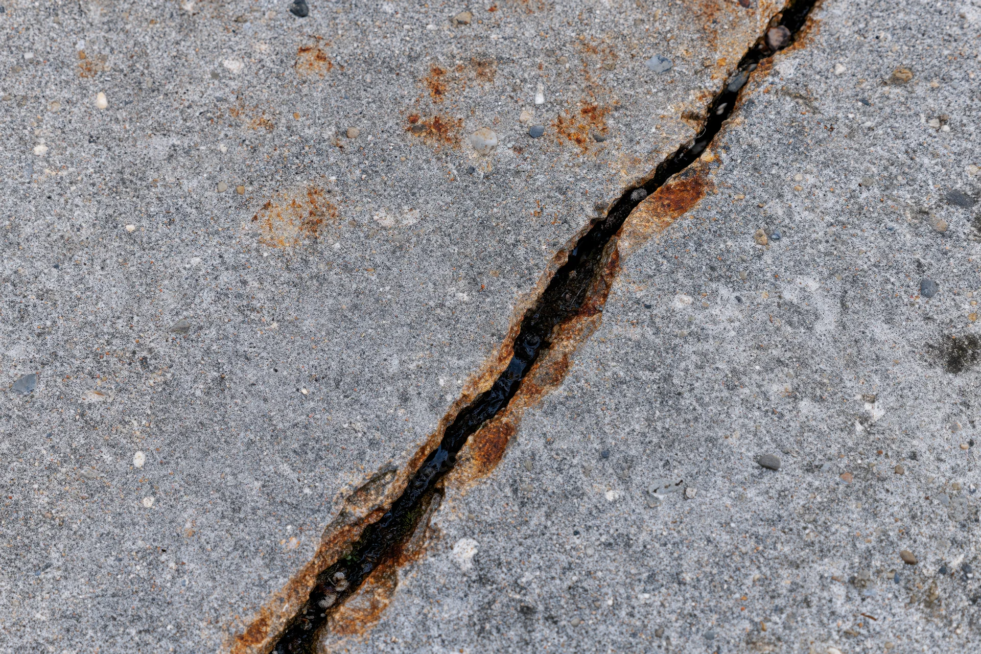 Diagonal crack in concrete pavement filled with black sealant