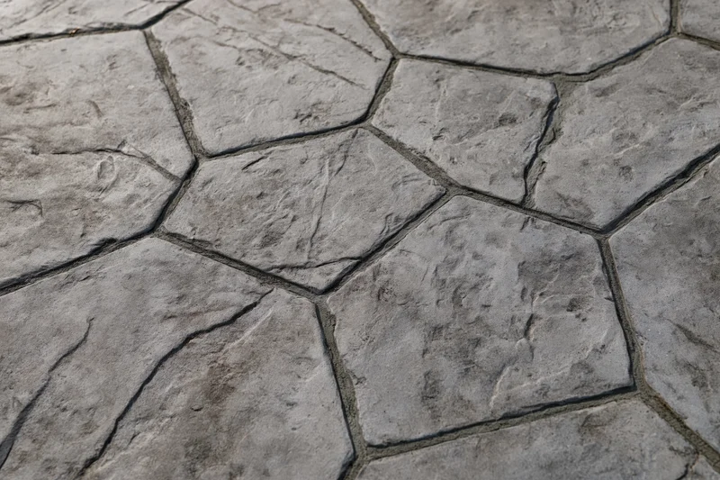 Close-up overhead view of stamped concrete paving with irregular stone pattern and textured surface